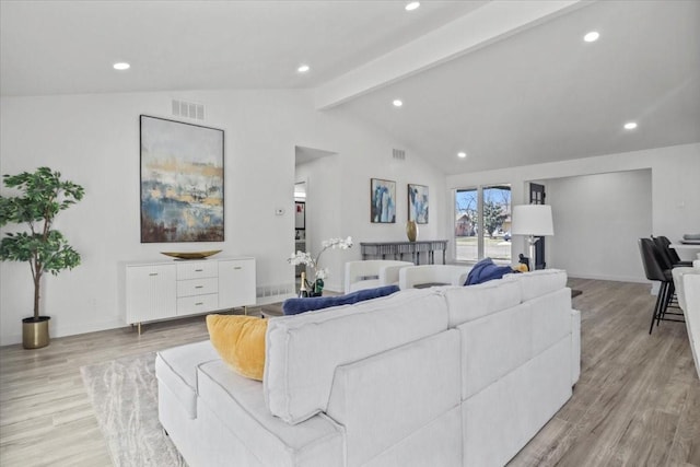 living room featuring lofted ceiling with beams and light hardwood / wood-style flooring