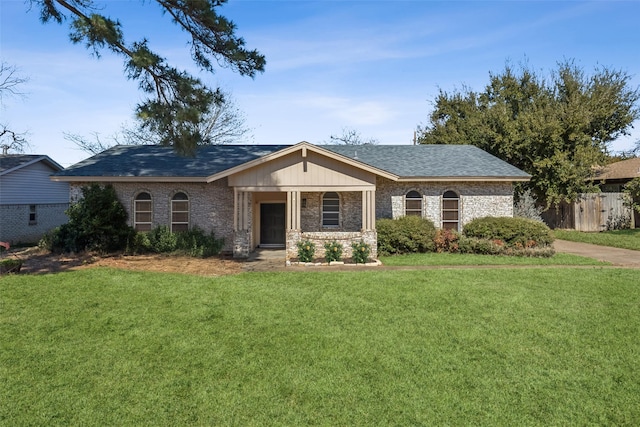 ranch-style house with a shingled roof, fence, a front lawn, and brick siding