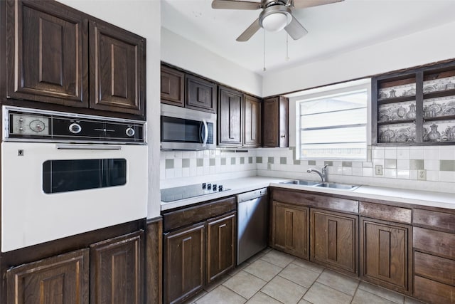 kitchen with appliances with stainless steel finishes, a sink, light countertops, dark brown cabinets, and backsplash