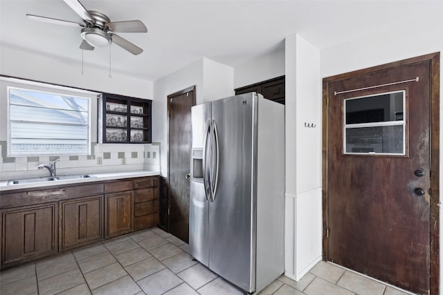 kitchen with light tile patterned flooring, a sink, light countertops, stainless steel refrigerator with ice dispenser, and backsplash