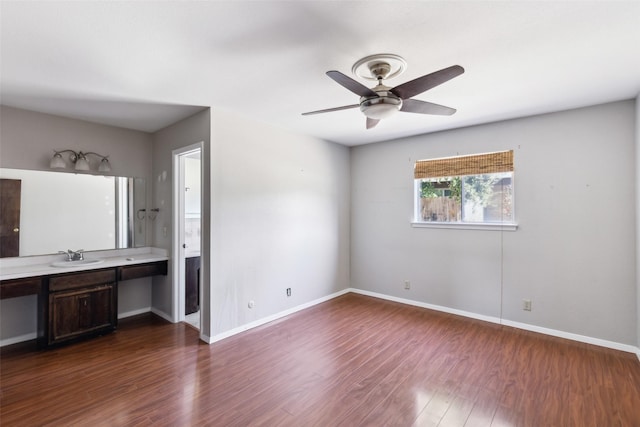 interior space featuring ceiling fan, baseboards, wood finished floors, and vanity