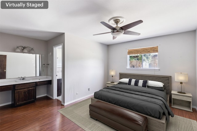 bedroom with dark wood-type flooring, a sink, a ceiling fan, baseboards, and ensuite bath