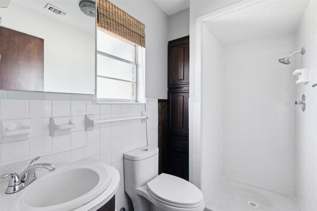 bathroom with a stall shower, visible vents, a sink, and toilet