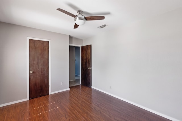 unfurnished bedroom with baseboards, visible vents, dark wood finished floors, and a ceiling fan