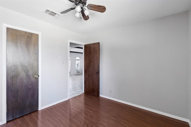 unfurnished bedroom featuring ceiling fan, baseboards, visible vents, and dark wood finished floors