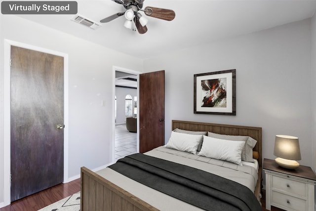 bedroom featuring dark wood-style floors, visible vents, baseboards, and a ceiling fan