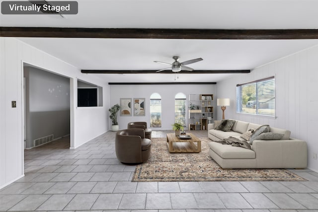 living area featuring beam ceiling, light tile patterned floors, visible vents, ceiling fan, and wood walls