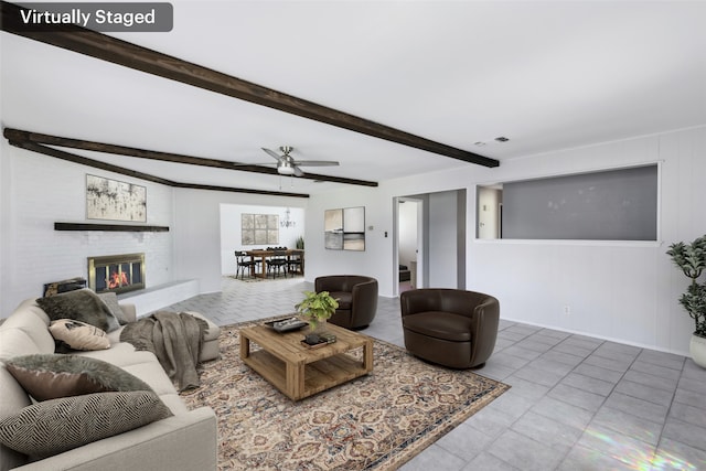 living room featuring a brick fireplace, beam ceiling, visible vents, and ceiling fan