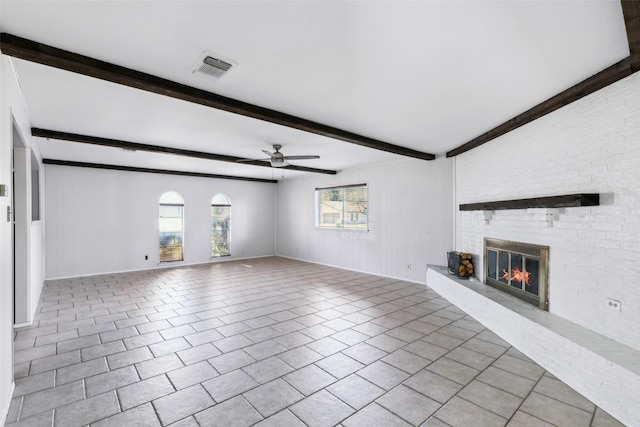 unfurnished living room with light tile patterned floors, visible vents, a ceiling fan, a brick fireplace, and beamed ceiling