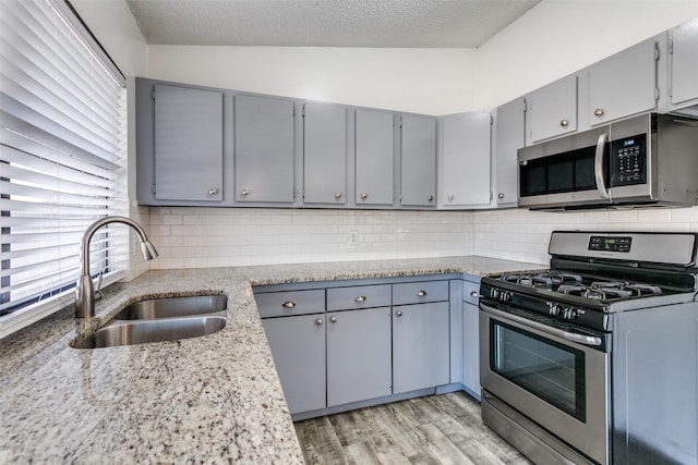 kitchen with vaulted ceiling, tasteful backsplash, sink, gray cabinetry, and stainless steel appliances