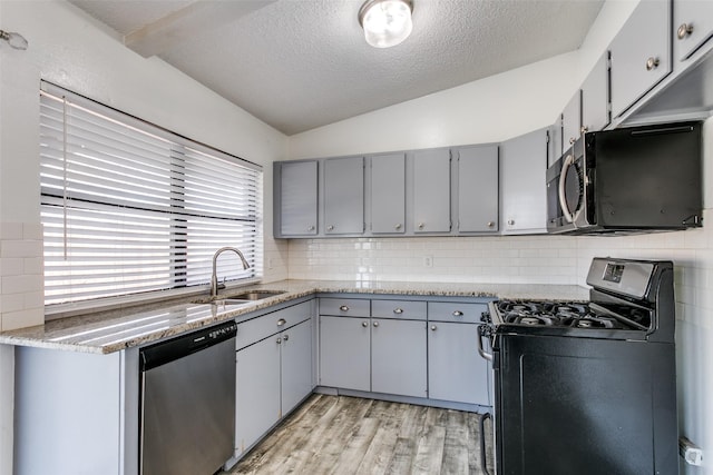 kitchen featuring lofted ceiling, sink, gray cabinetry, stainless steel appliances, and a textured ceiling