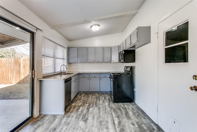 kitchen featuring lofted ceiling, sink, gray cabinets, stainless steel appliances, and decorative backsplash