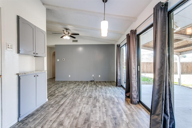 unfurnished living room featuring lofted ceiling with beams, ceiling fan, and light wood-type flooring