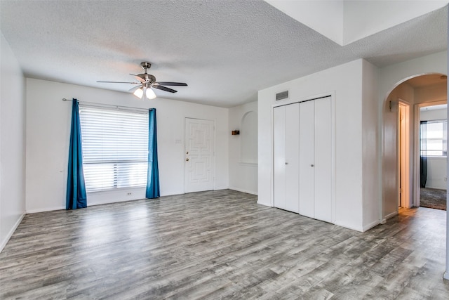 interior space featuring ceiling fan, a textured ceiling, multiple windows, and two closets