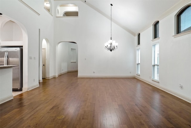 unfurnished living room with hardwood / wood-style flooring, a chandelier, and high vaulted ceiling