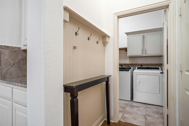 clothes washing area featuring cabinets and separate washer and dryer