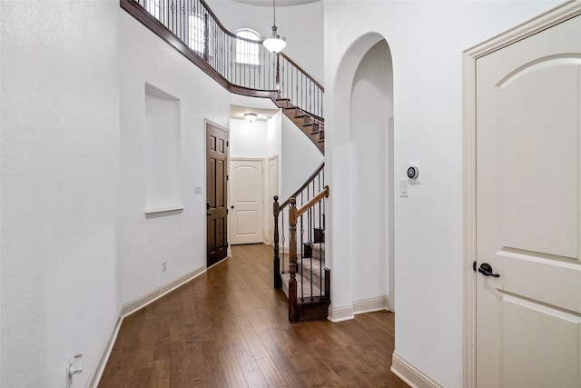 corridor with a high ceiling and dark hardwood / wood-style flooring