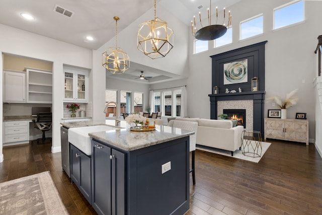 kitchen with dark wood-type flooring, stainless steel dishwasher, a glass covered fireplace, and built in desk