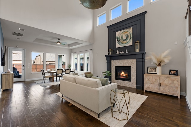 living room with a tray ceiling, dark hardwood / wood-style flooring, and a wealth of natural light