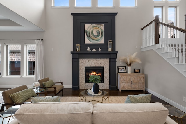 living room featuring a high ceiling, a healthy amount of sunlight, and dark wood-type flooring