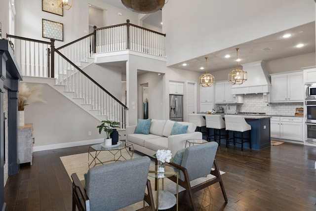 living room with a towering ceiling, dark hardwood / wood-style floors, a chandelier, and sink