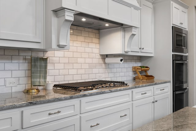 kitchen with tasteful backsplash, white cabinetry, appliances with stainless steel finishes, and light stone counters