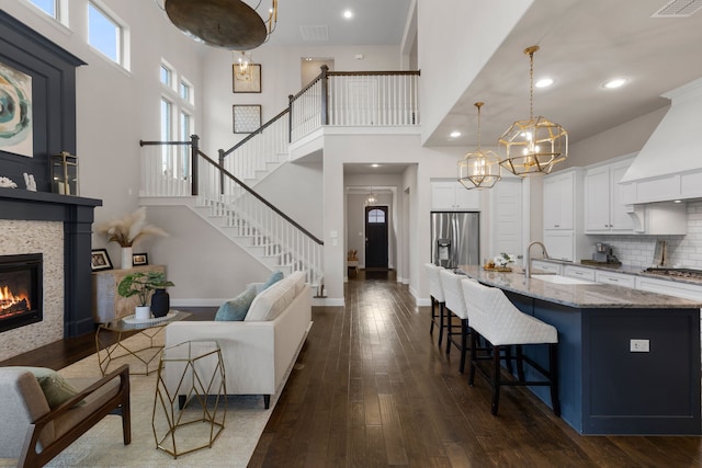 living room featuring stairs, baseboards, dark wood-style floors, and a tiled fireplace