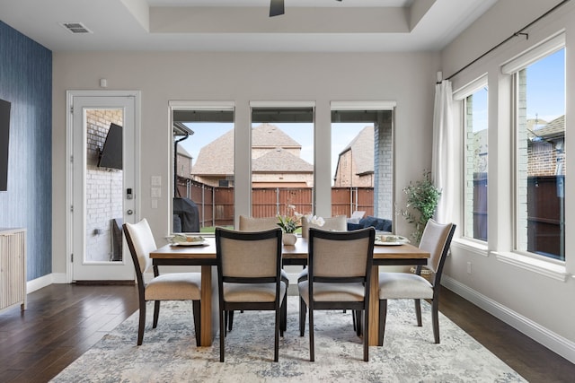 dining space featuring a raised ceiling, ceiling fan, and dark hardwood / wood-style flooring