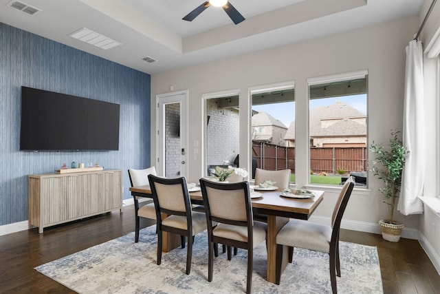 dining space with a tray ceiling, dark hardwood / wood-style floors, and ceiling fan