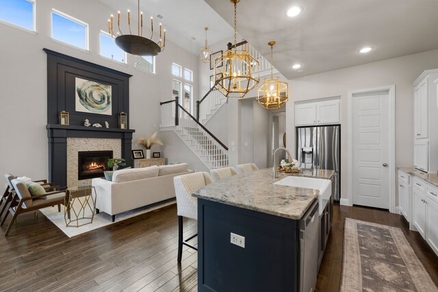 living room with a towering ceiling, a fireplace, dark hardwood / wood-style flooring, and sink