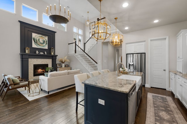 kitchen featuring a kitchen bar, light stone countertops, a glass covered fireplace, and dark wood finished floors