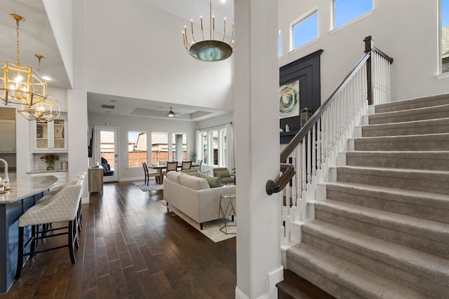 interior space with dark hardwood / wood-style flooring, ceiling fan with notable chandelier, and a high ceiling