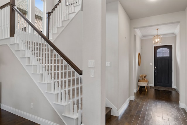 entryway featuring crown molding, dark hardwood / wood-style floors, a wealth of natural light, and an inviting chandelier