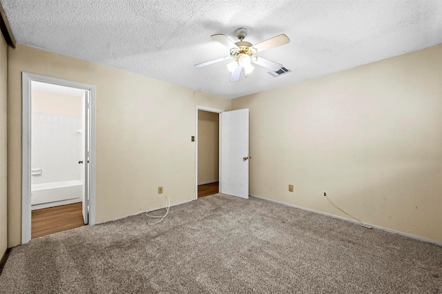 unfurnished bedroom with ceiling fan, connected bathroom, carpet floors, and a textured ceiling