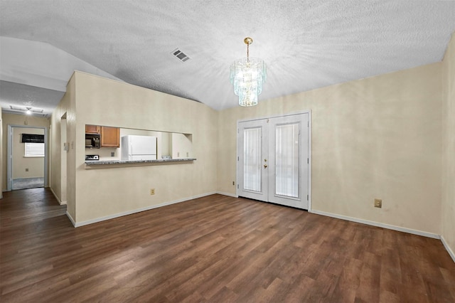 interior space featuring lofted ceiling, dark wood-type flooring, a notable chandelier, and a textured ceiling