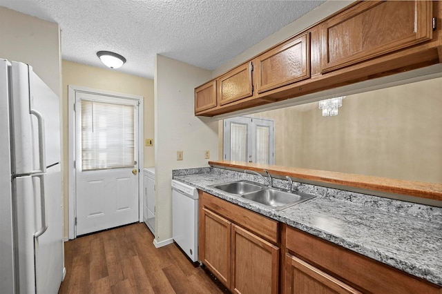 kitchen with dark wood-type flooring, white appliances, sink, and a textured ceiling