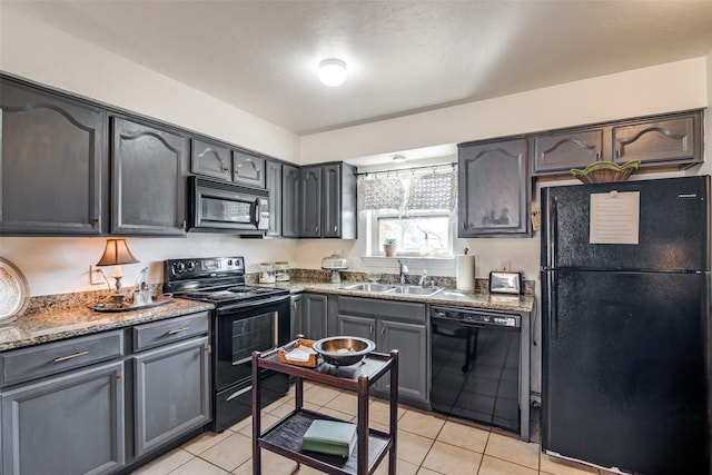 kitchen with light tile patterned flooring, dark stone counters, sink, and black appliances