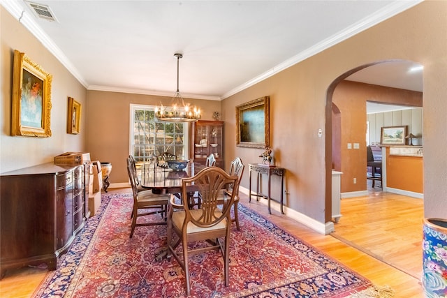 dining space featuring crown molding, an inviting chandelier, and hardwood / wood-style floors