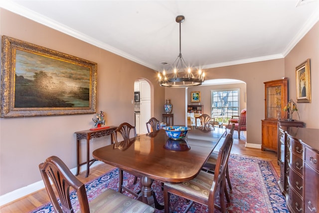 dining space with wood-type flooring, ornamental molding, and a chandelier