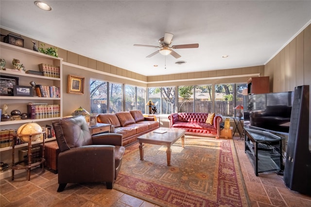 living room with ceiling fan and wood walls