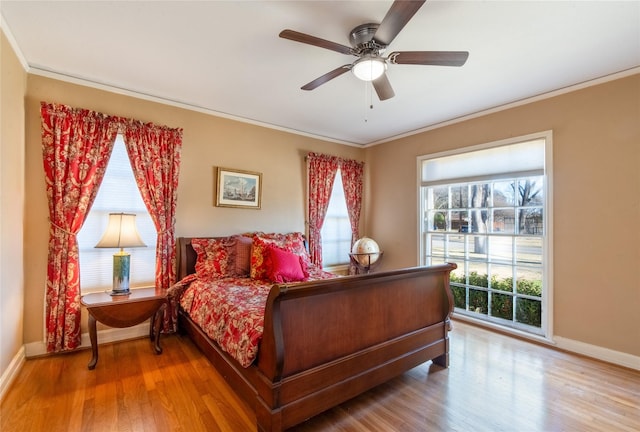 bedroom with hardwood / wood-style flooring, ceiling fan, ornamental molding, and multiple windows