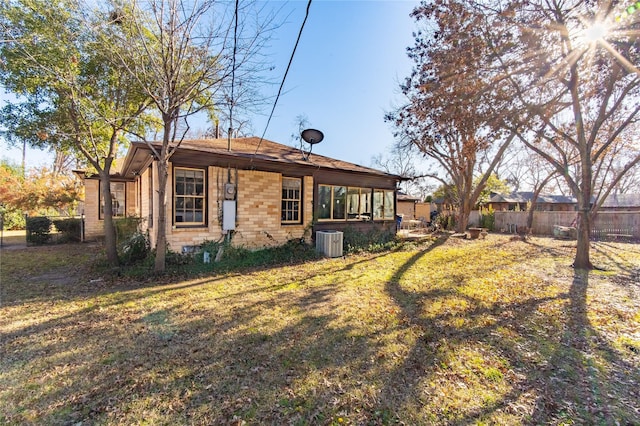 rear view of house featuring central AC and a lawn