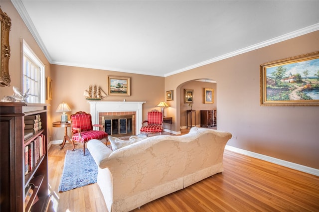 living room featuring ornamental molding, a brick fireplace, and light hardwood / wood-style floors