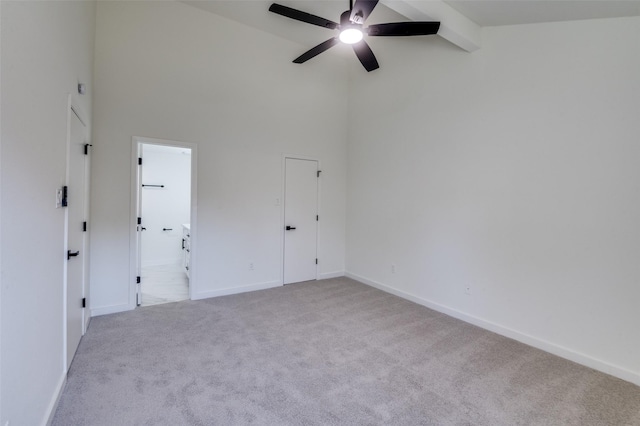 carpeted empty room with beam ceiling, high vaulted ceiling, and ceiling fan