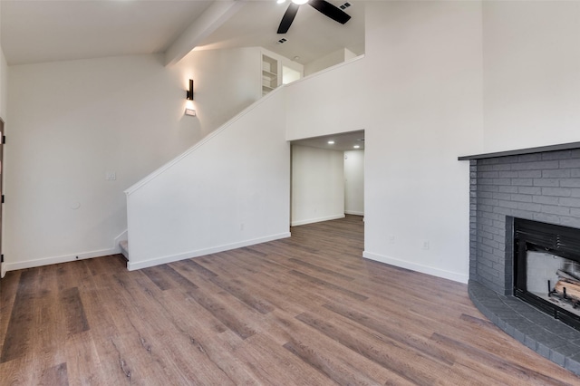 unfurnished living room featuring beam ceiling, wood-type flooring, high vaulted ceiling, ceiling fan, and a fireplace