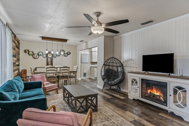 living room with dark hardwood / wood-style flooring, ceiling fan, a textured ceiling, and wood walls