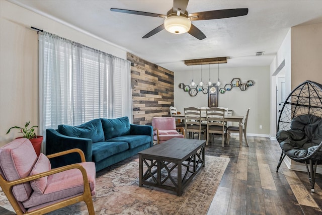 living room with dark hardwood / wood-style flooring, ceiling fan, and wood walls