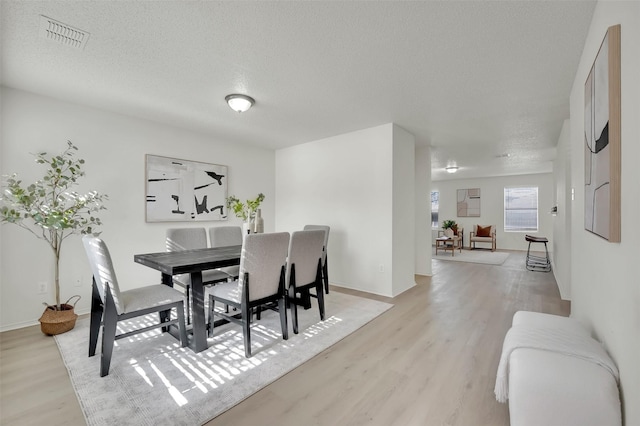 dining room featuring a textured ceiling and light wood-type flooring