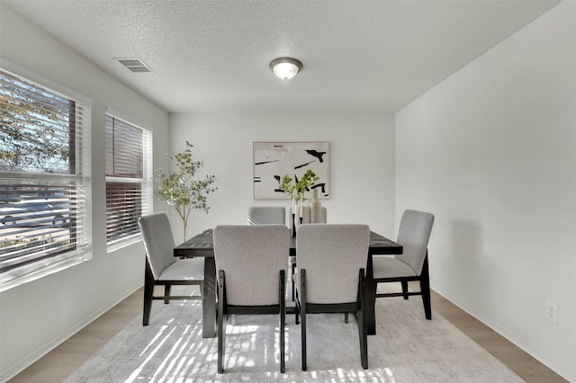 dining room with plenty of natural light, a textured ceiling, and light hardwood / wood-style floors