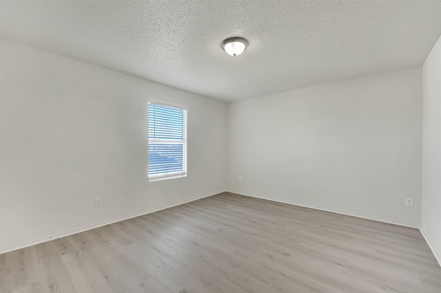 empty room with light hardwood / wood-style flooring and a textured ceiling